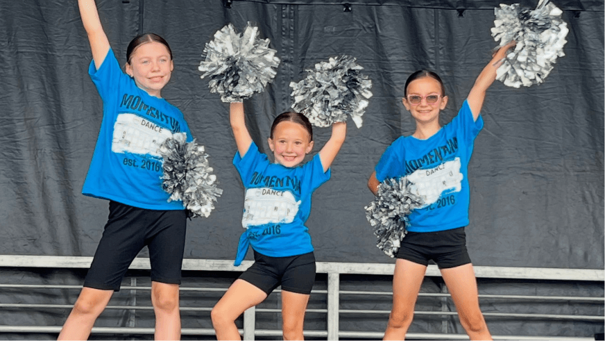 Jr. Hawkettes dancers in blue shirts holding silver pom poms